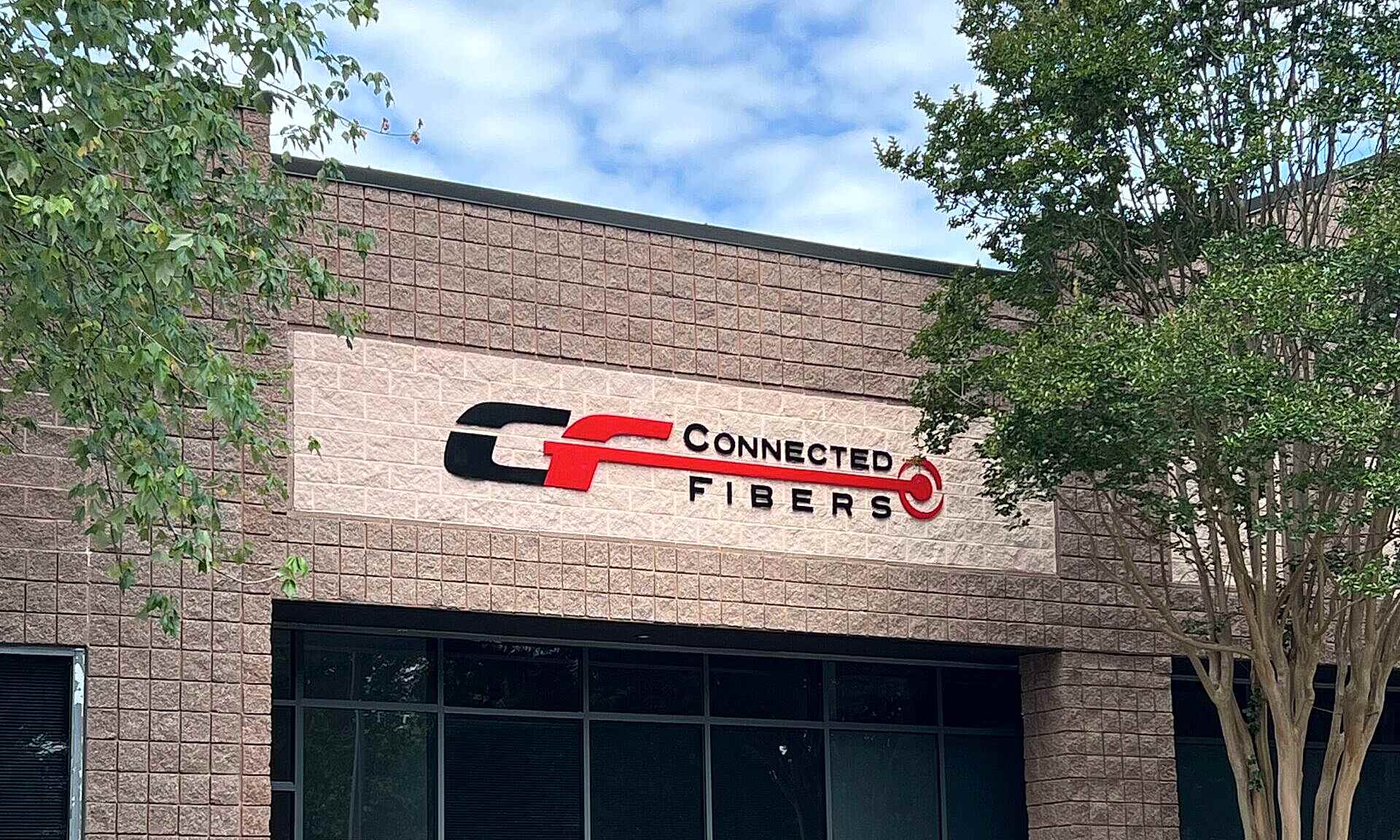 Laser-cut acrylic sign reading 'Connected Fibers,' featuring 1/2-inch thick painted letters pin mounted to an exterior wall in Roswell, GA.