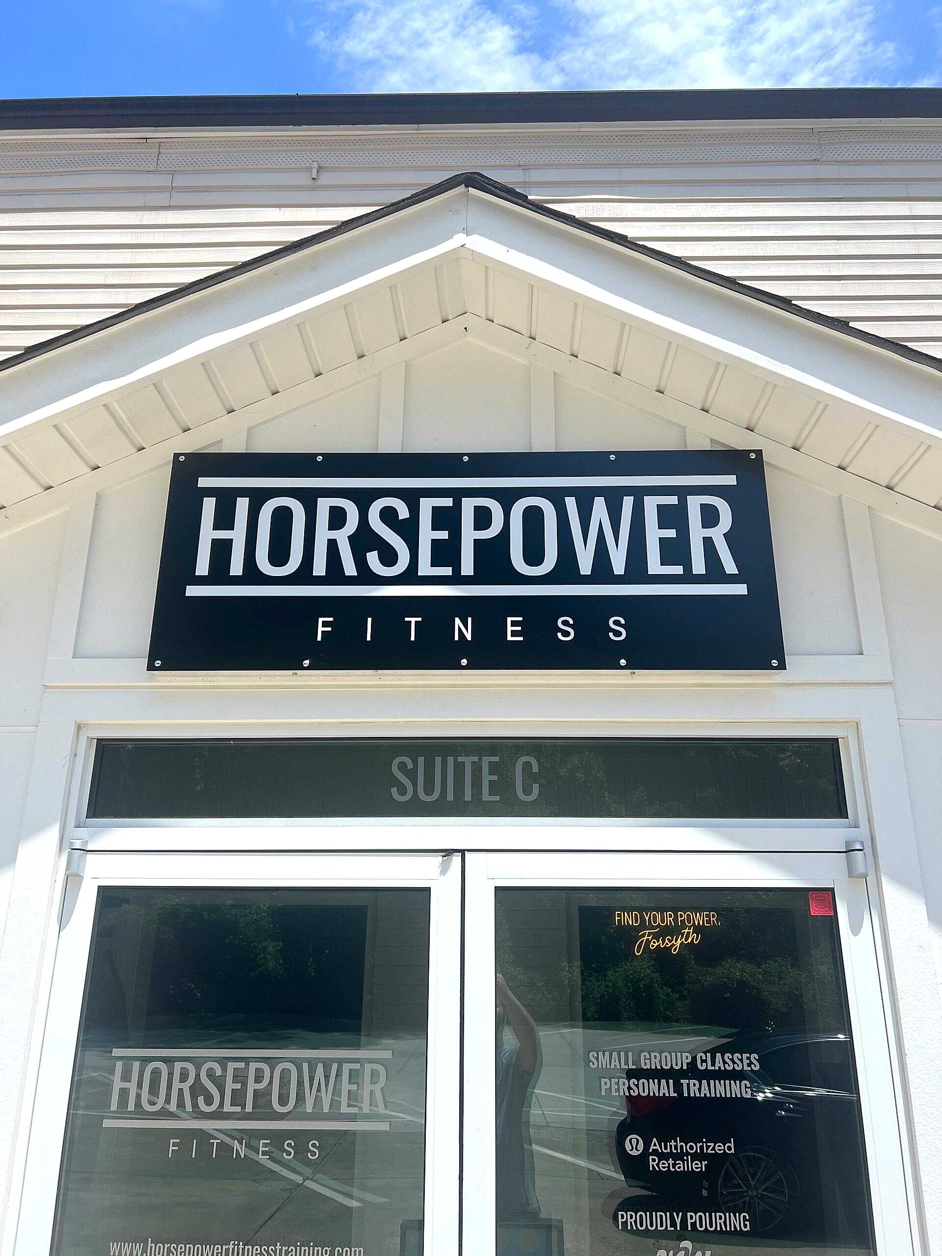 Matte black panel sign with bold white vinyl lettering reading 'Horsepower Fitness,' mounted on an exterior wall in Cumming, GA.