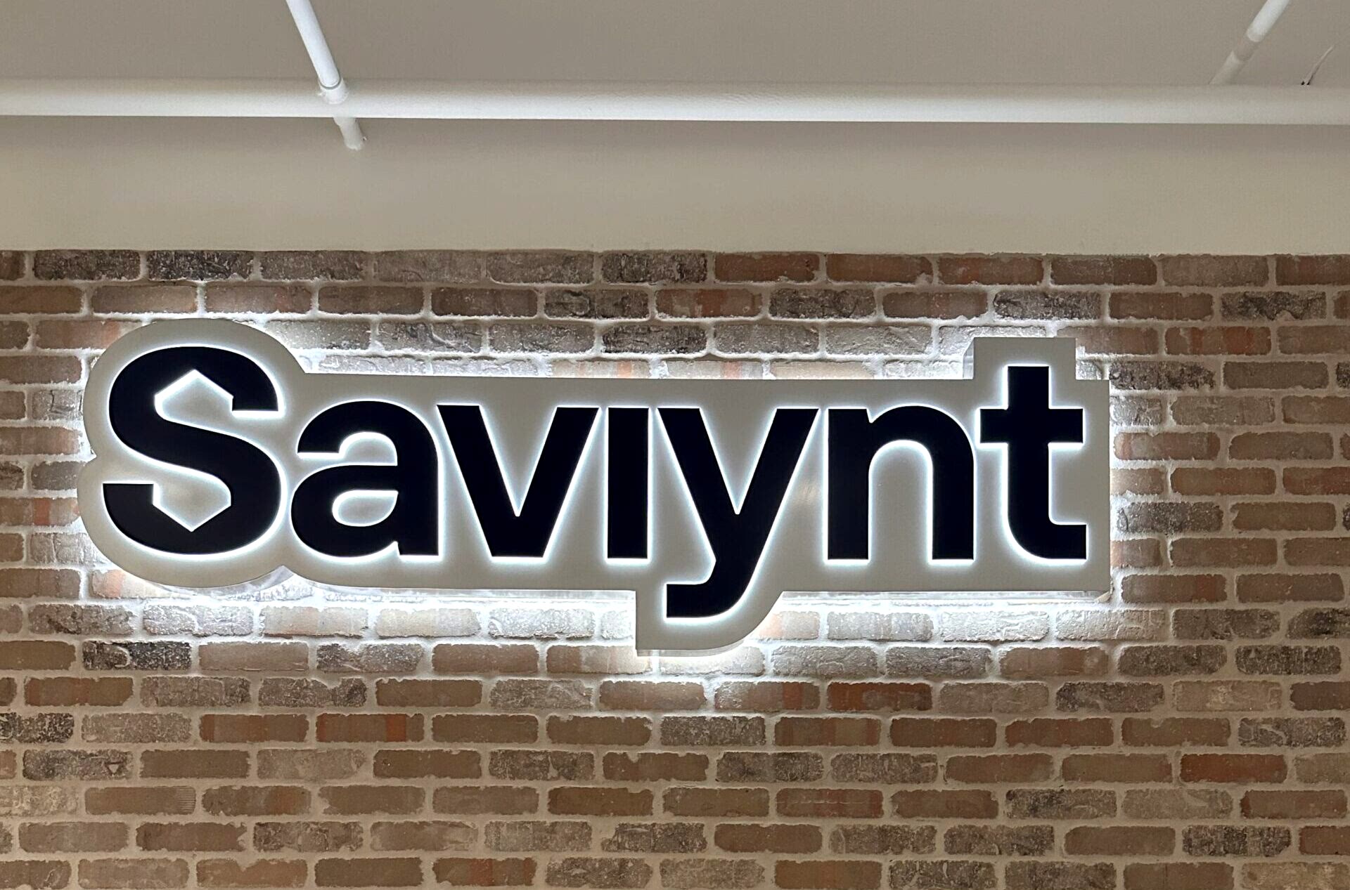 Halo-lit and side-lit custom lobby sign for Saviynt in Atlanta, GA, featuring their new logo mounted on the main lobby wall