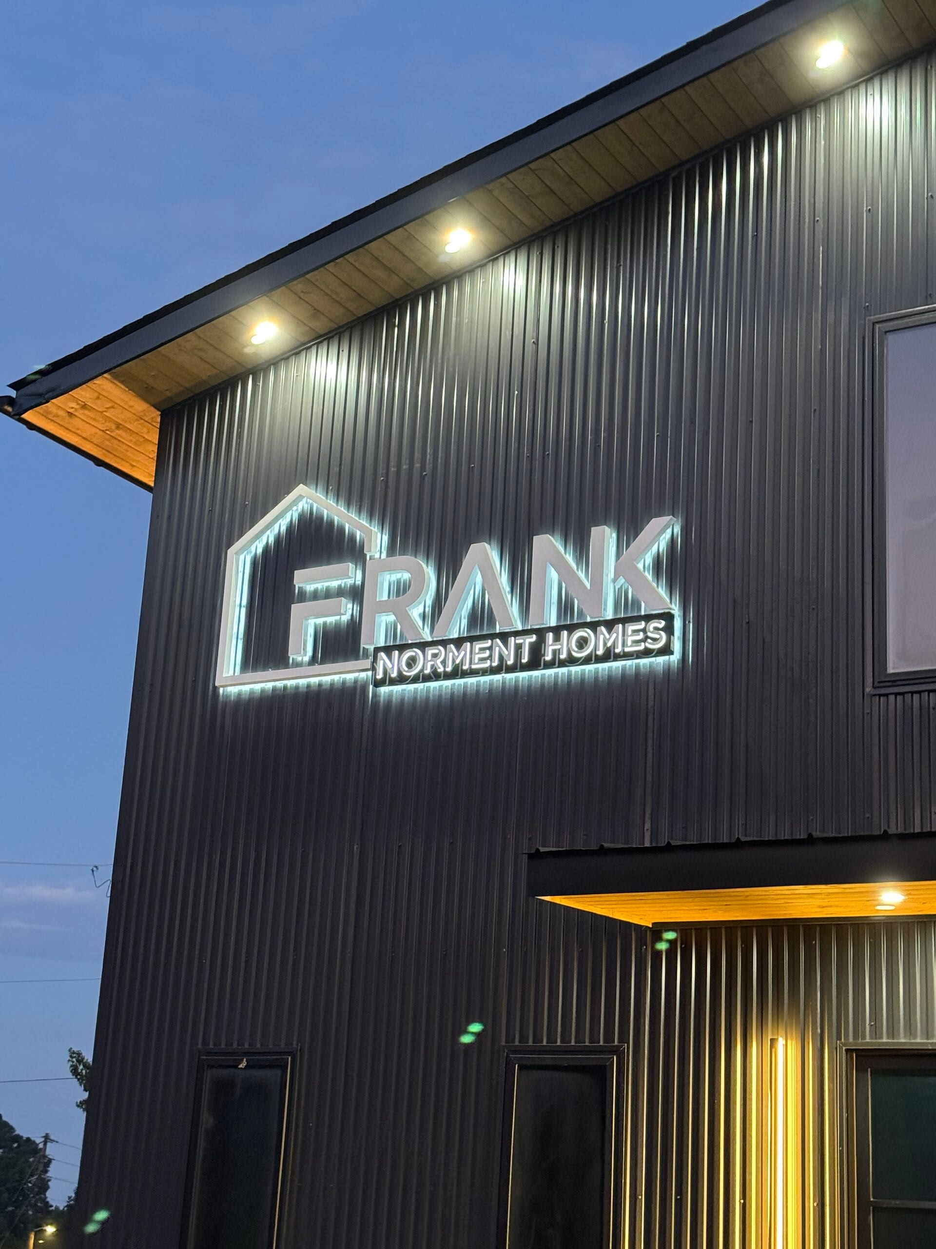 Illuminated building sign for Frank Norment Homes in Bremen, GA, featuring channel letters for 'Frank' and logo, with a lit pan and push-through letters for 'Norment Homes.'