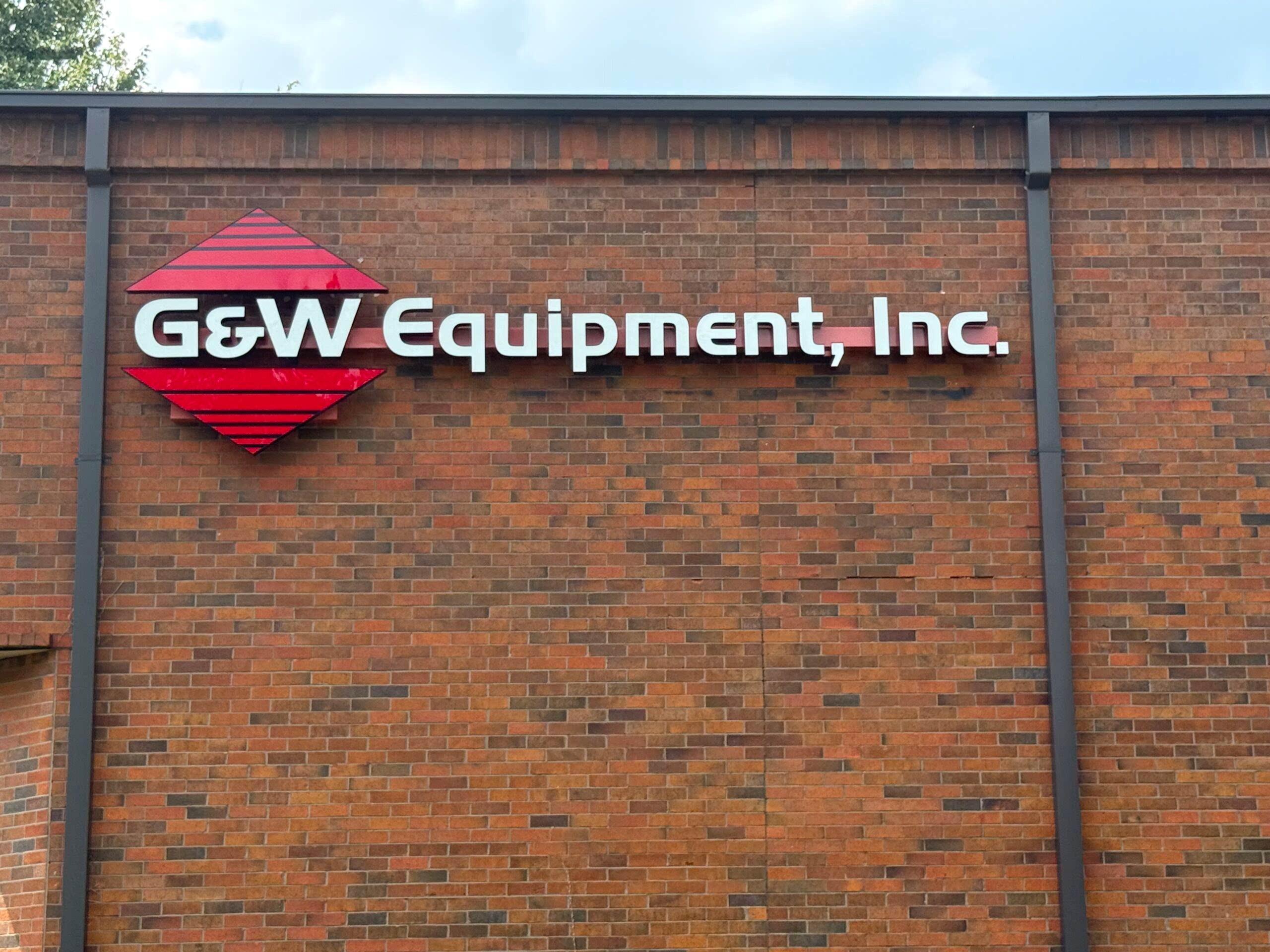 Exterior G&W Equipment, Inc. building sign in Atlanta, GA, featuring dimensional letters and the red G&W logo mounted on a brick wall.