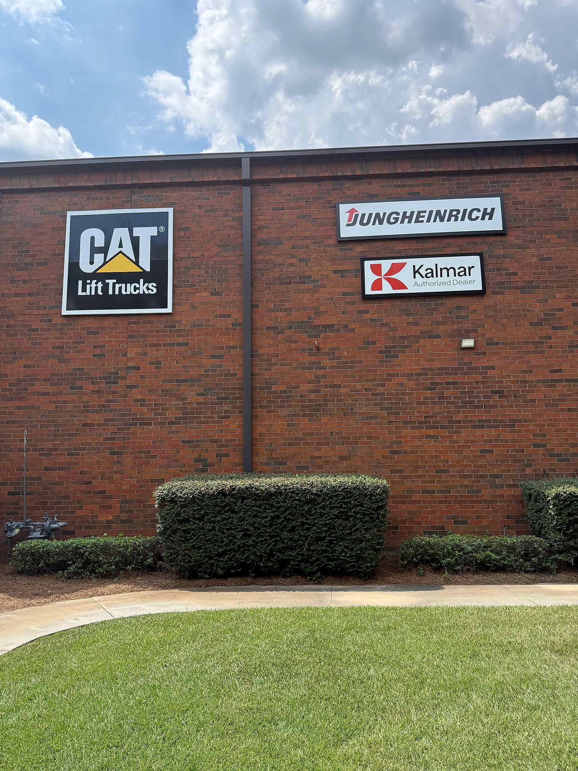 Exterior building signs for CAT Lift Trucks, Jungheinrich, and Kalmar mounted on the brick wall at G&W Equipment, Inc. in Atlanta, GA.