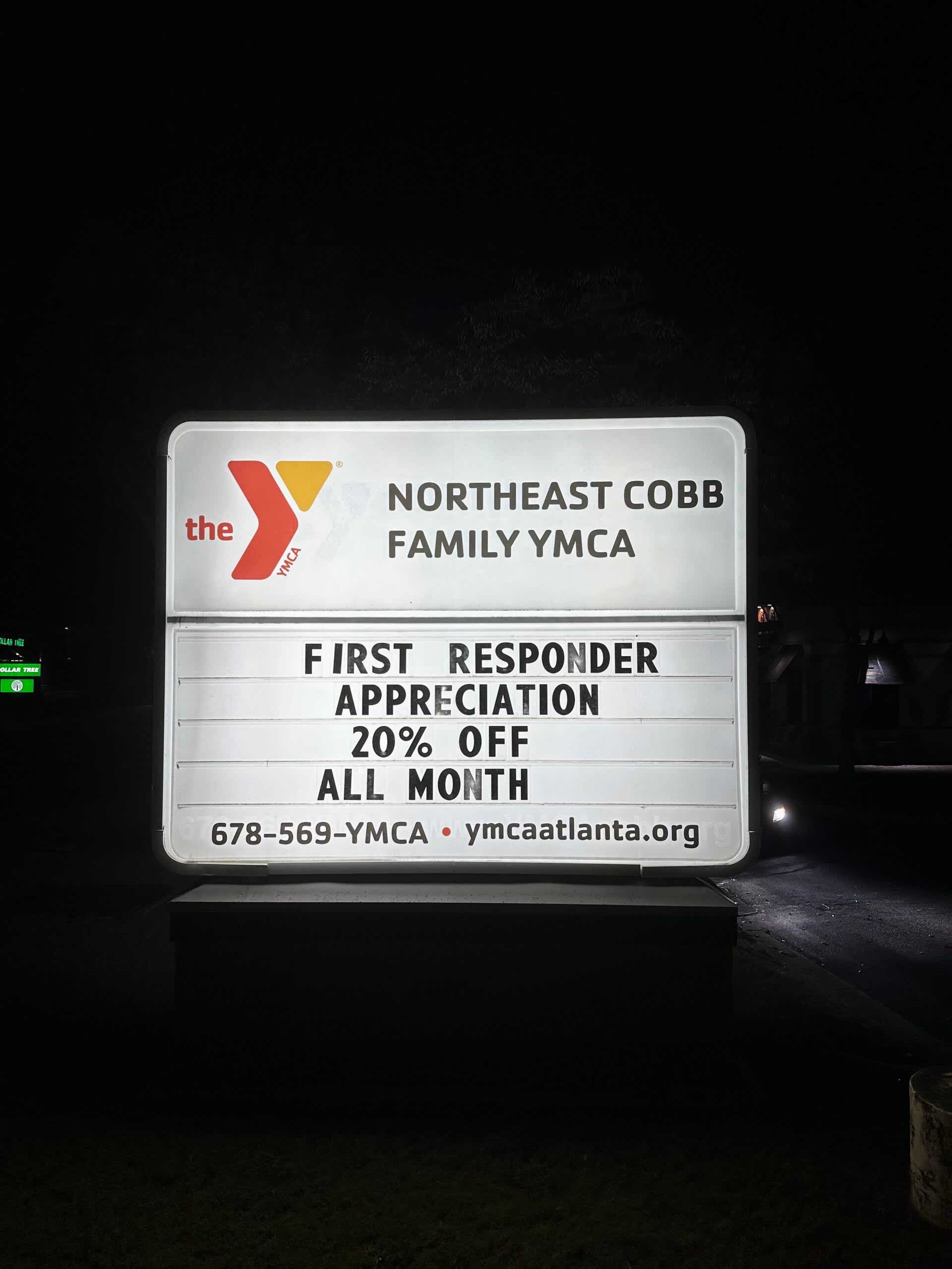 lluminated Northeast Cobb Family YMCA monument sign in Marietta, Georgia, shown at night with updated graphics and a reader board message.